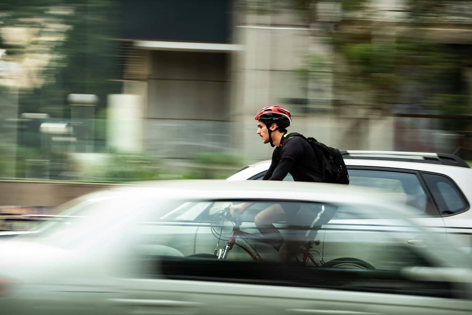 Fietser met helm rijdt langs een auto in stadsverkeer