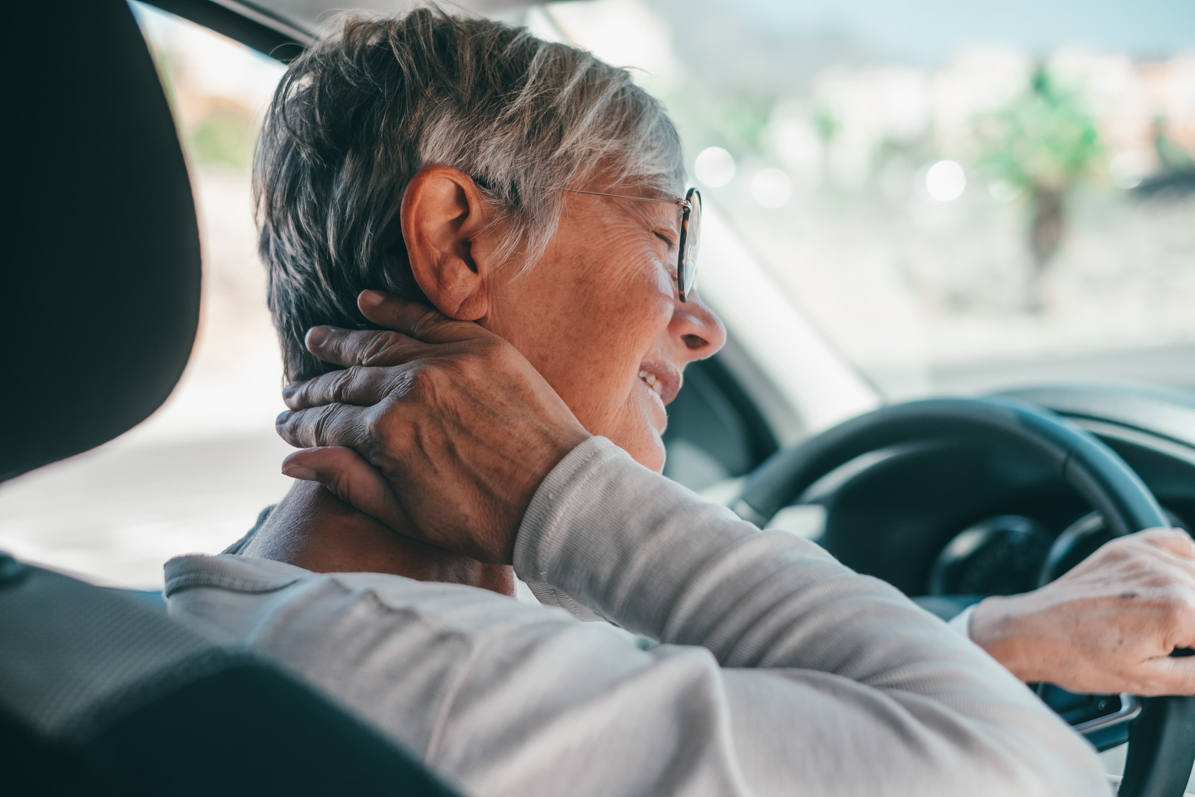Vrouw met beide handen om haar nek, nekpijn na whiplash